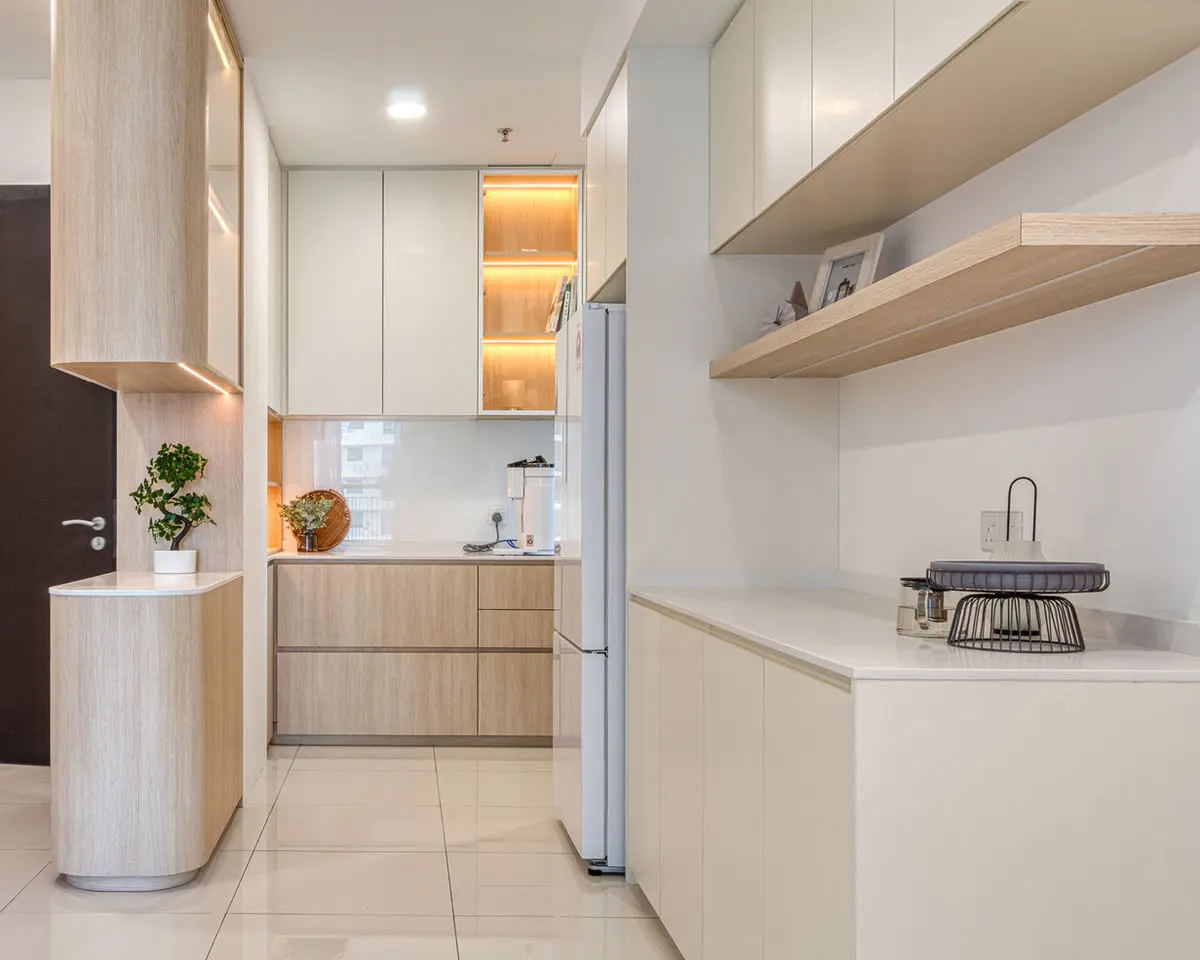 Compact kitchen with pale timber cabinets, a curved counter end and backlit display niche