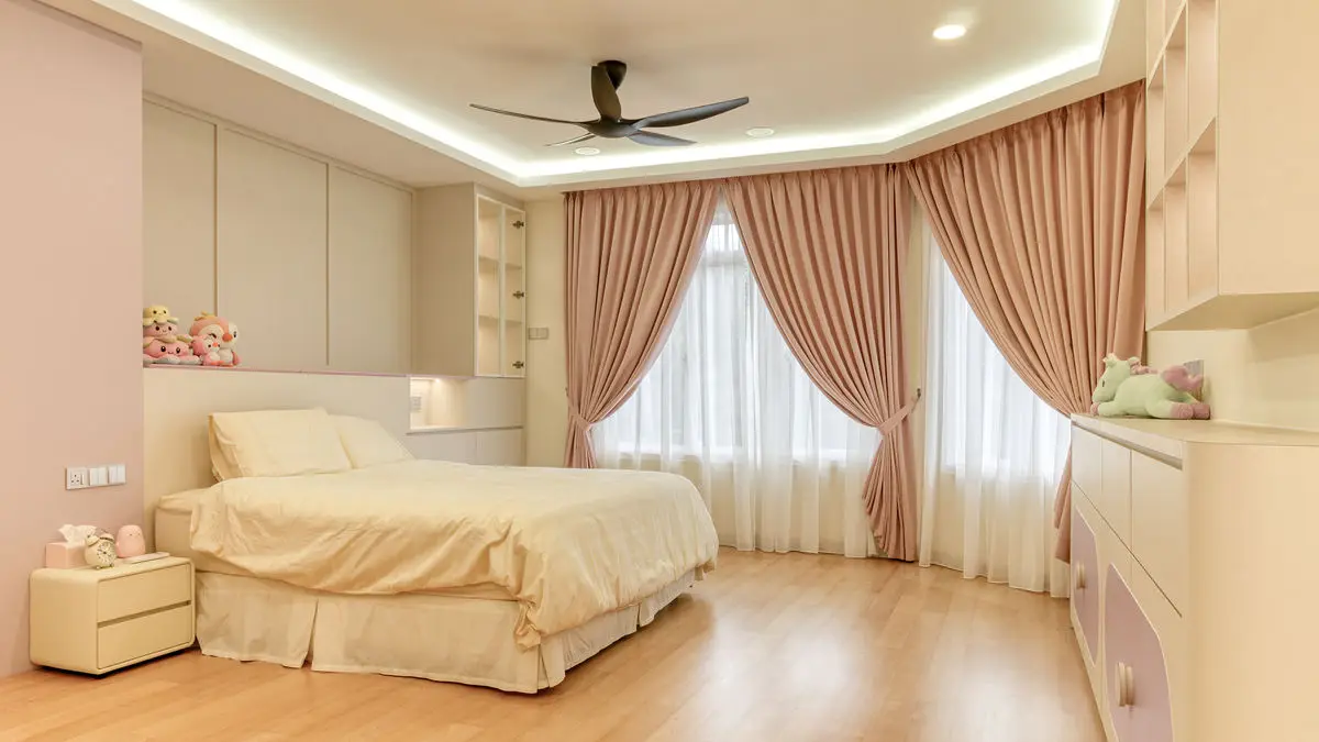 Girl's bedroom in cream and pink with a ceiling fan, built-in wardrobes and pink curtains