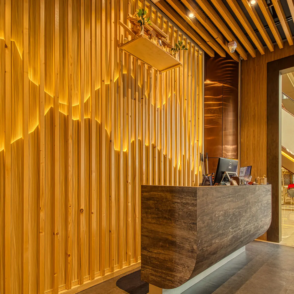 Restaurant reception desk in stone, against a backlit timber slat wall
