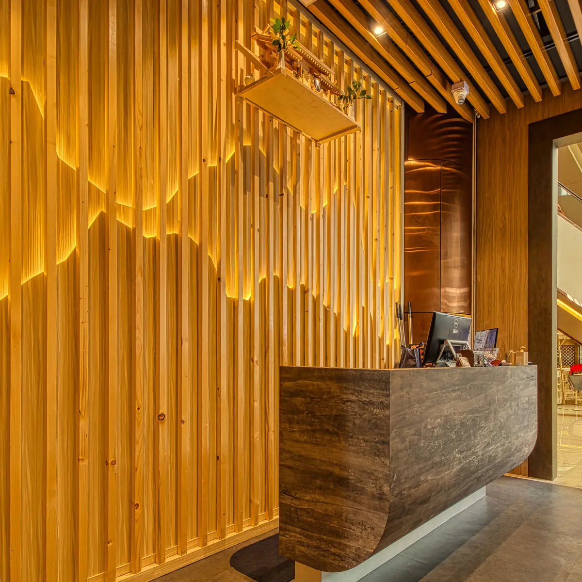 Restaurant reception desk in stone, against a backlit timber slat wall