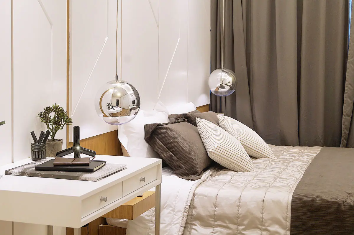 Bedroom with a white dressing desk, glass globe pendant lights and layered bedding