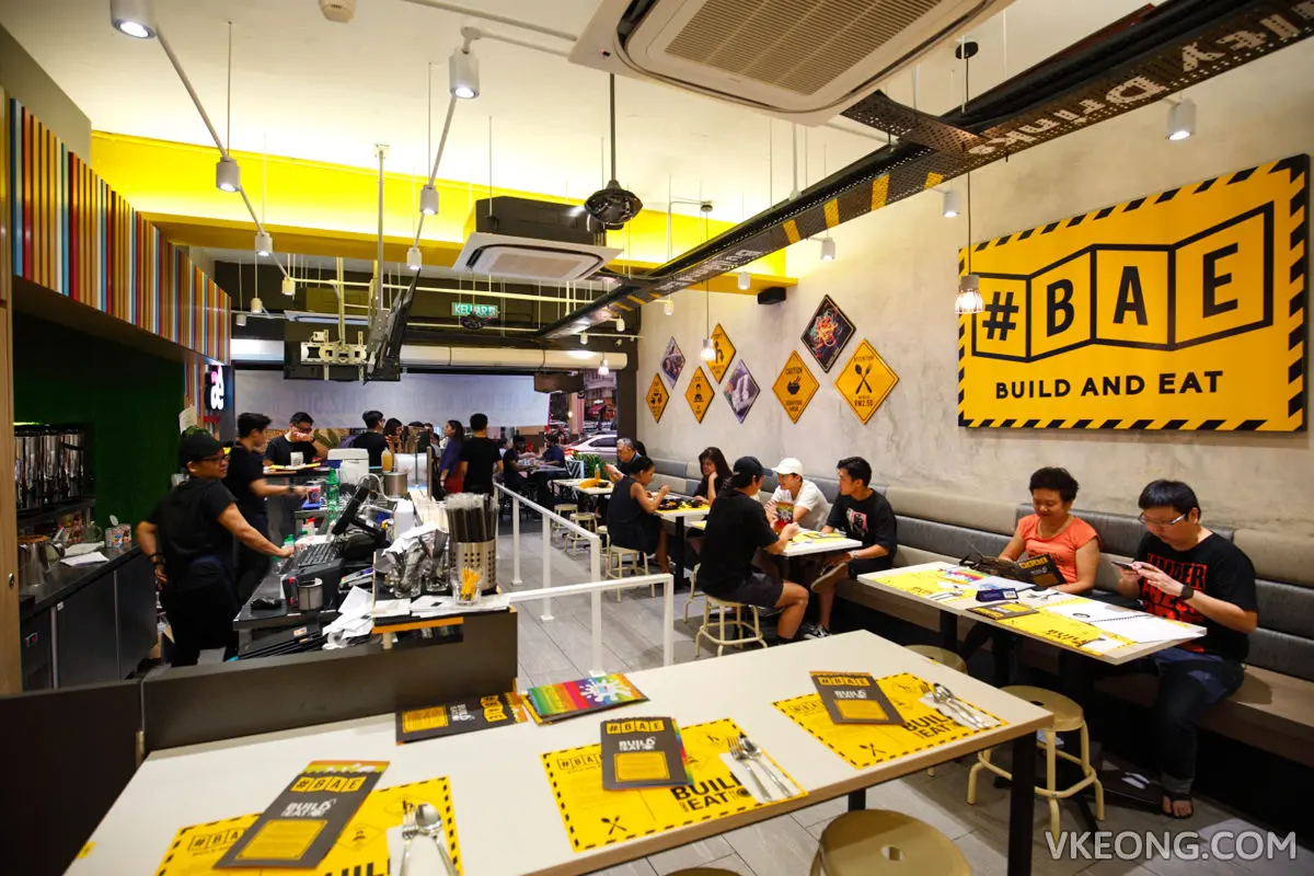 Casual restaurant with yellow signage, communal tables and an open kitchen
