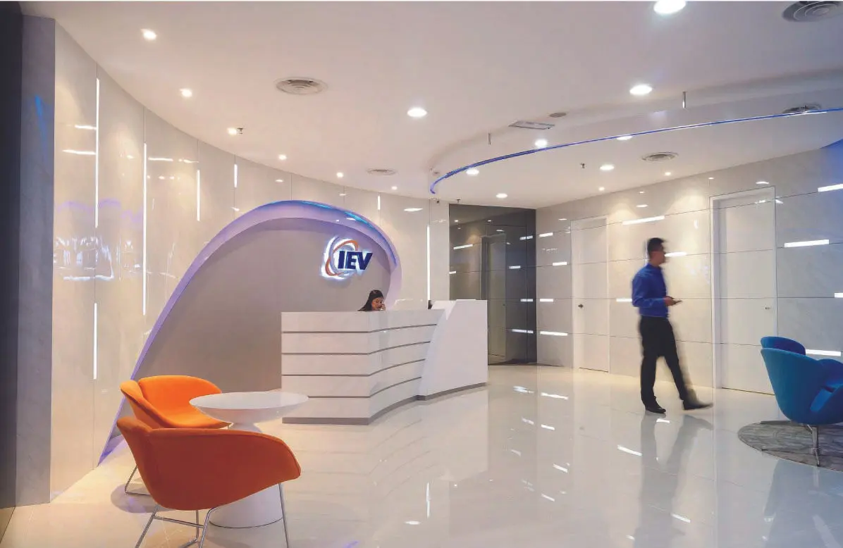 Office reception with a curved backlit feature wall, white counter and coloured chairs
