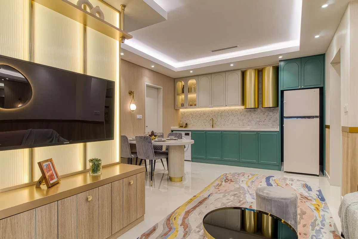 Living room with a timber TV wall, green kitchen cabinetry beyond and a patterned rug