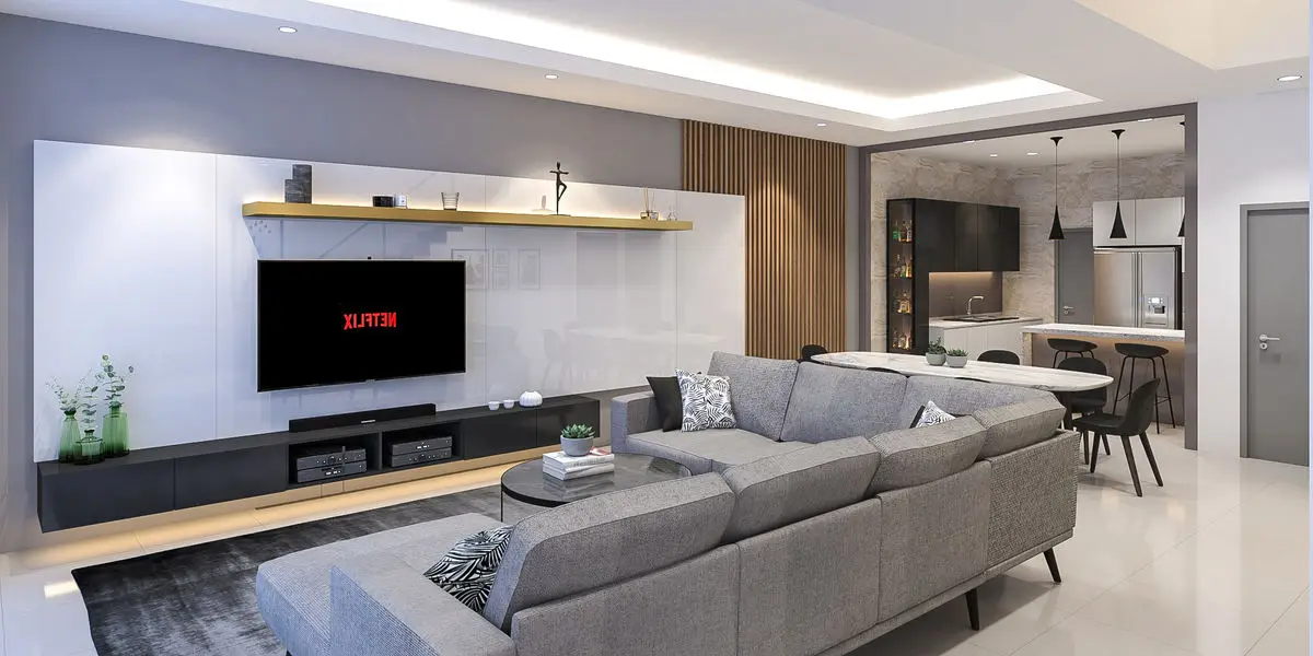 Living room with a wall-mounted TV, grey sectional sofa and open kitchen beyond