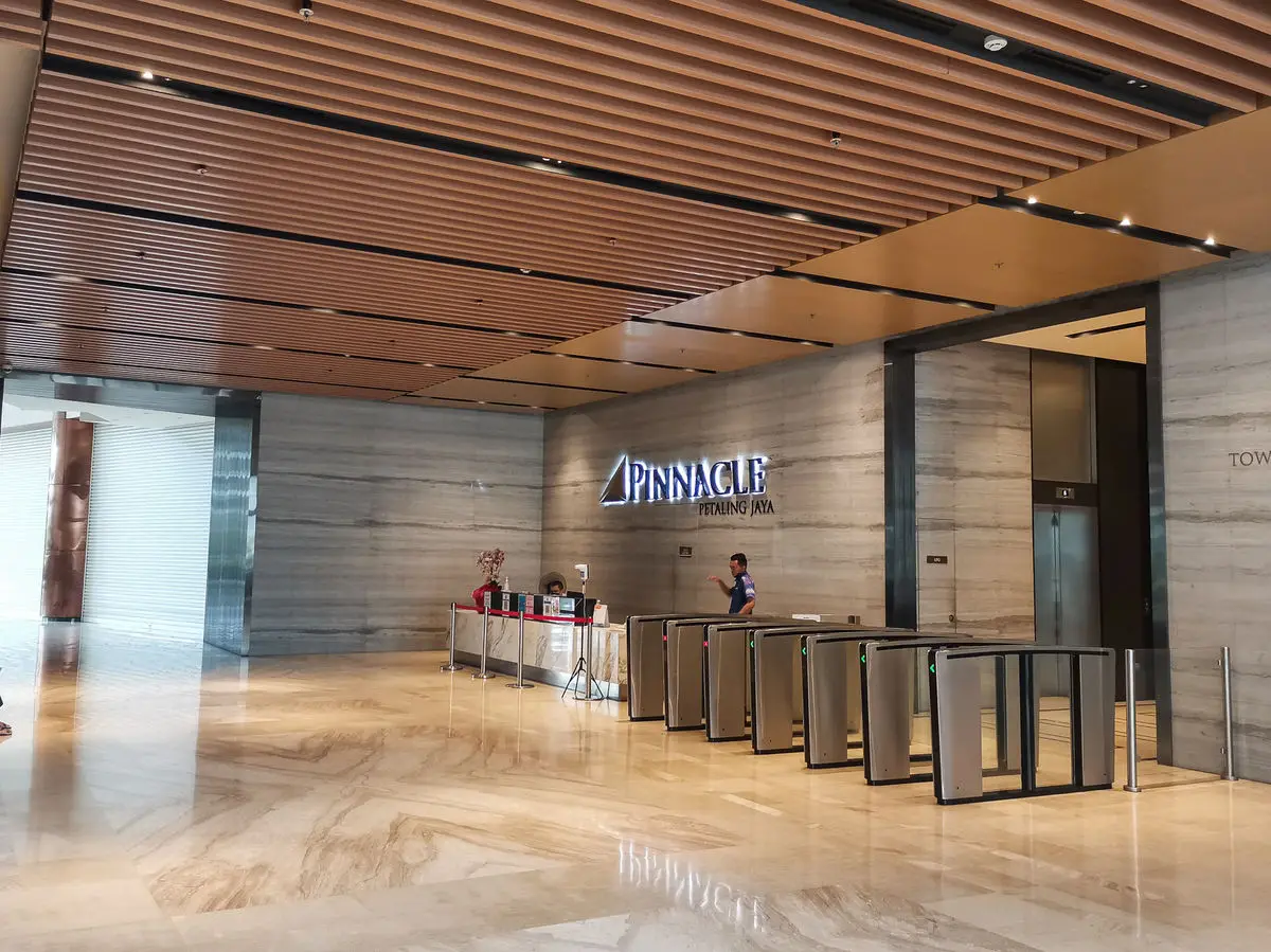 Tower lobby with security gates, a timber batten ceiling and marble flooring