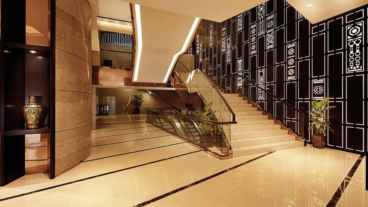 Hotel lobby with an escalator, patterned screen wall and timber panelling