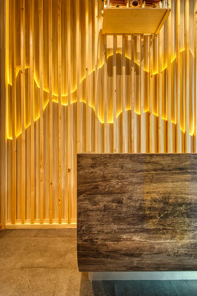 Stone-clad host counter with backlit timber slats behind