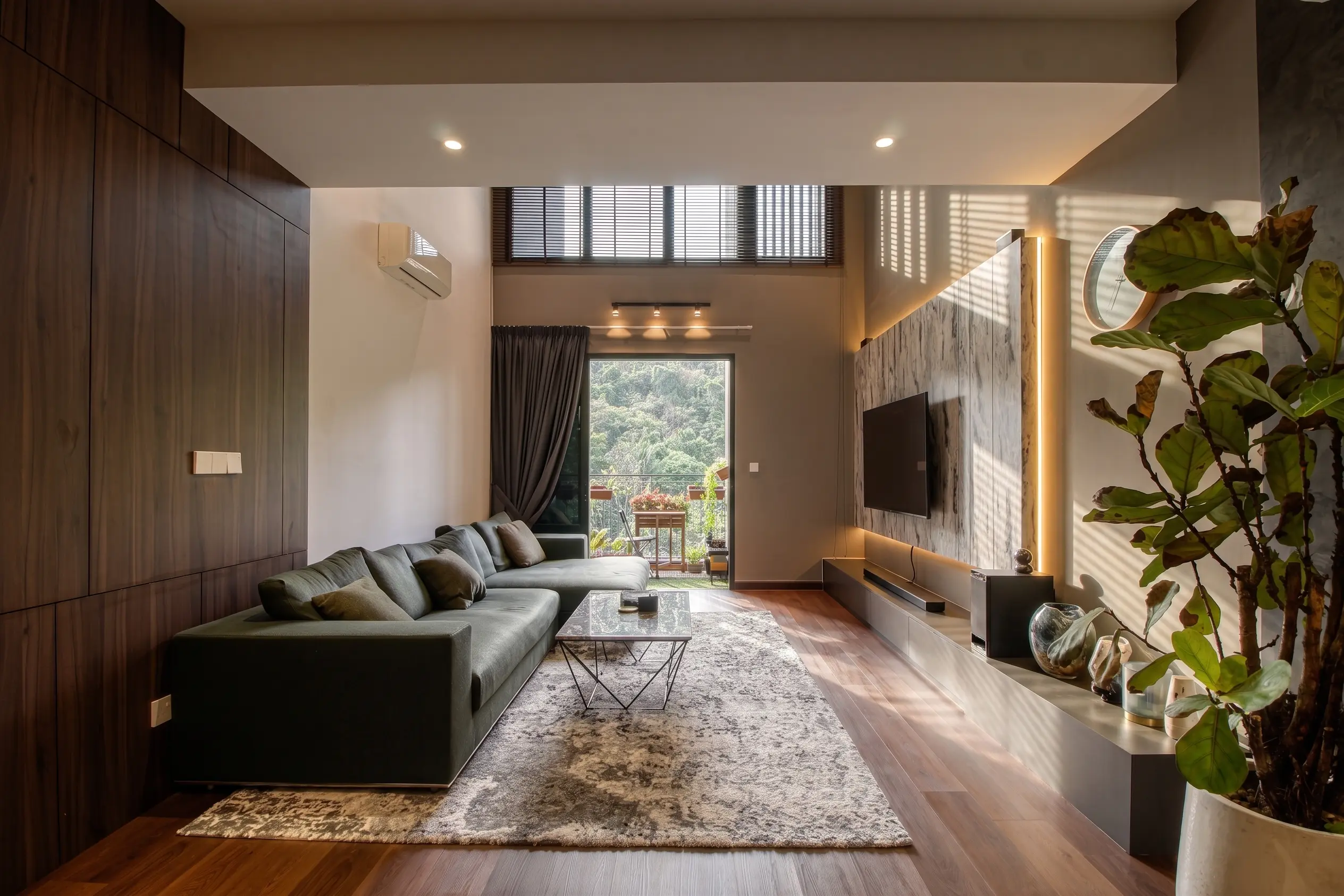 Daylit living room with olive sectional, walnut joinery, stone TV wall and jungle view