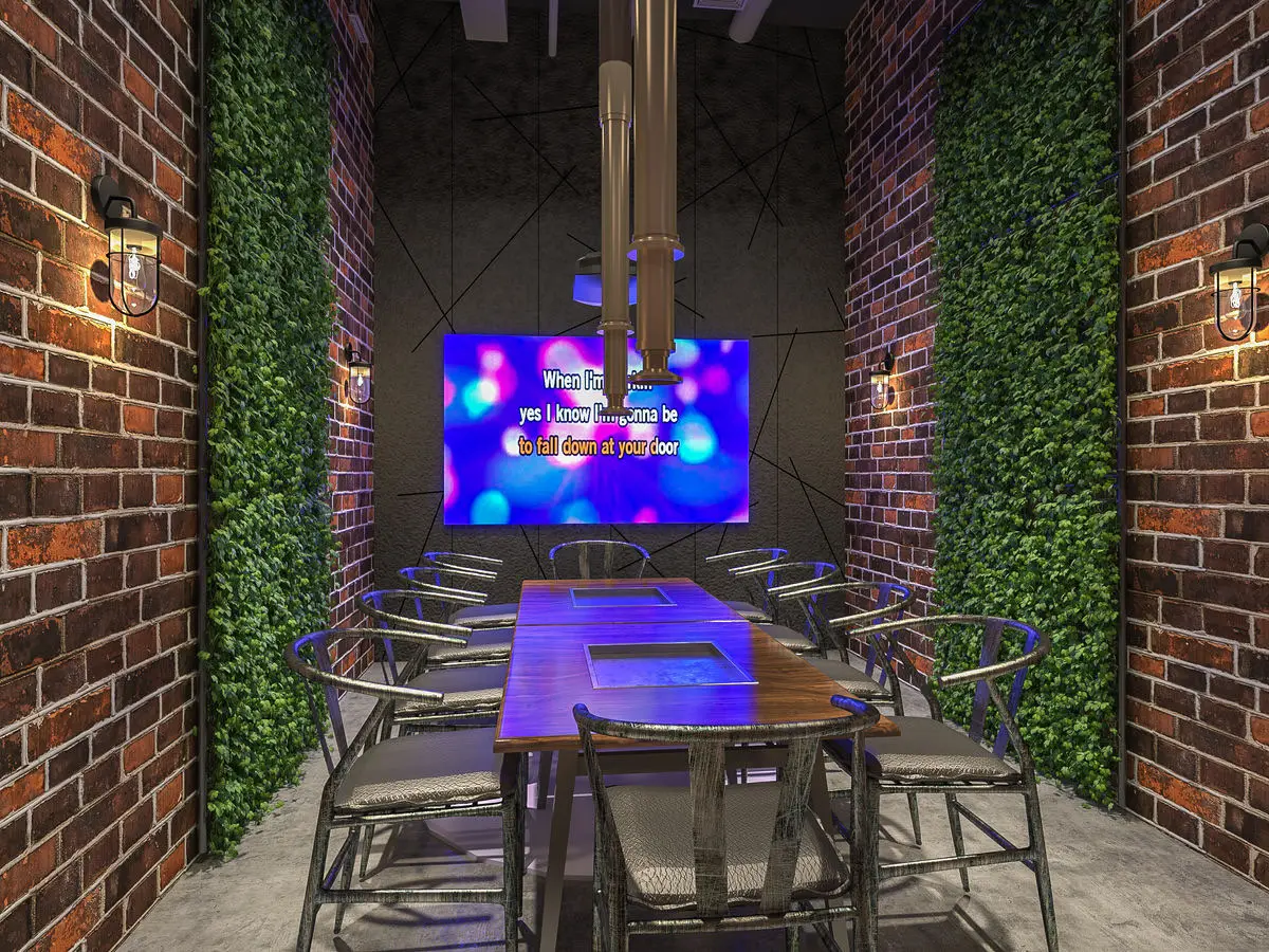 Private dining booth with planted walls, a video screen and metal chairs