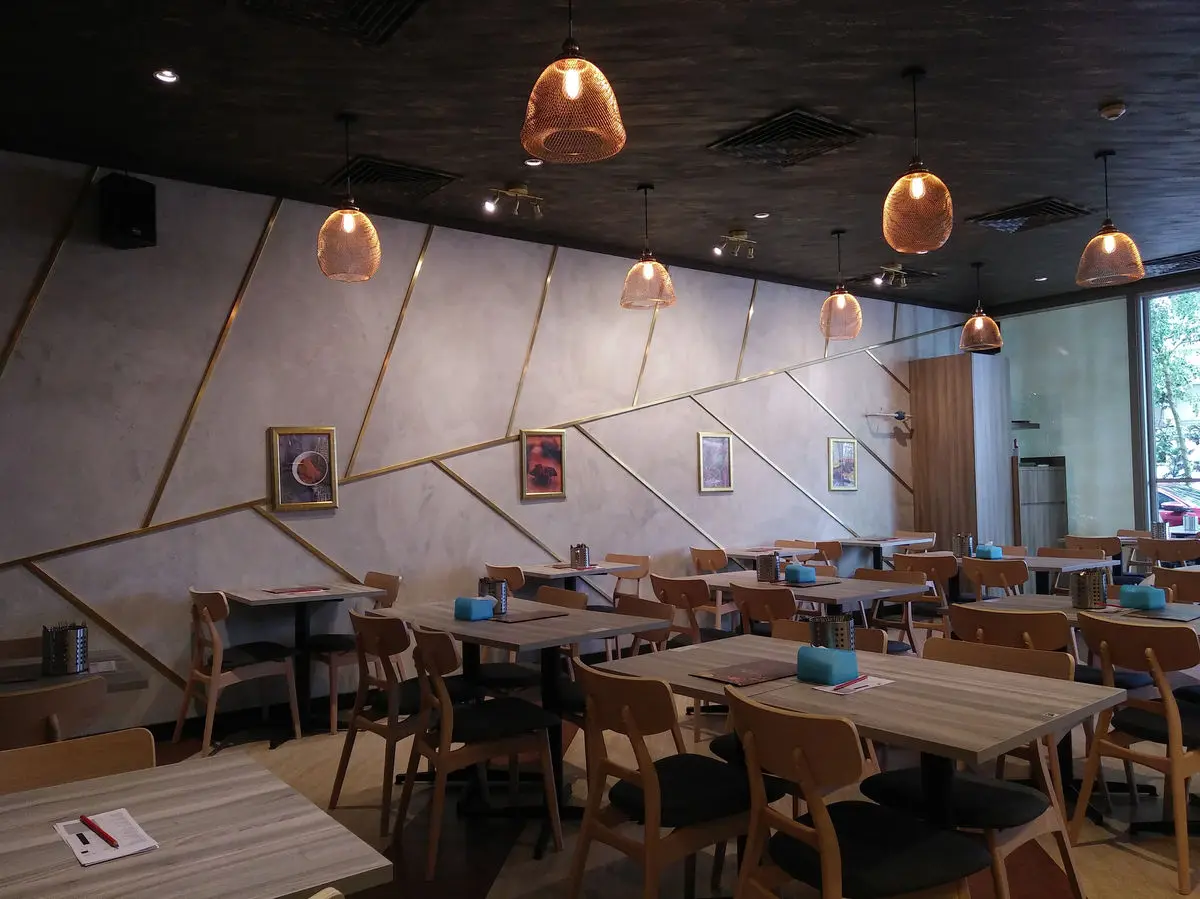 Dining area with concrete walls, brass line detailing and pendant lighting