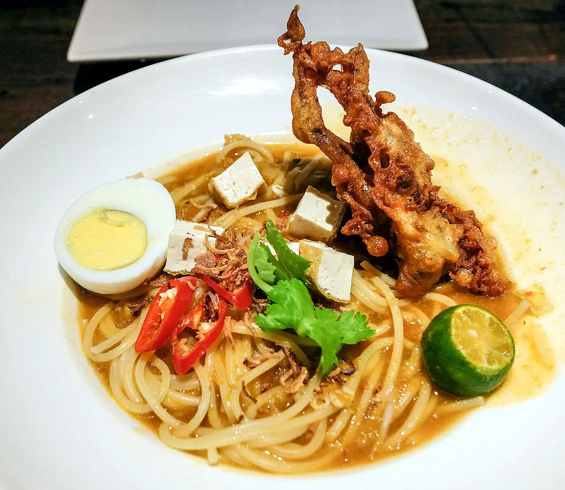 Plated noodle dish with fried chicken, egg and tofu