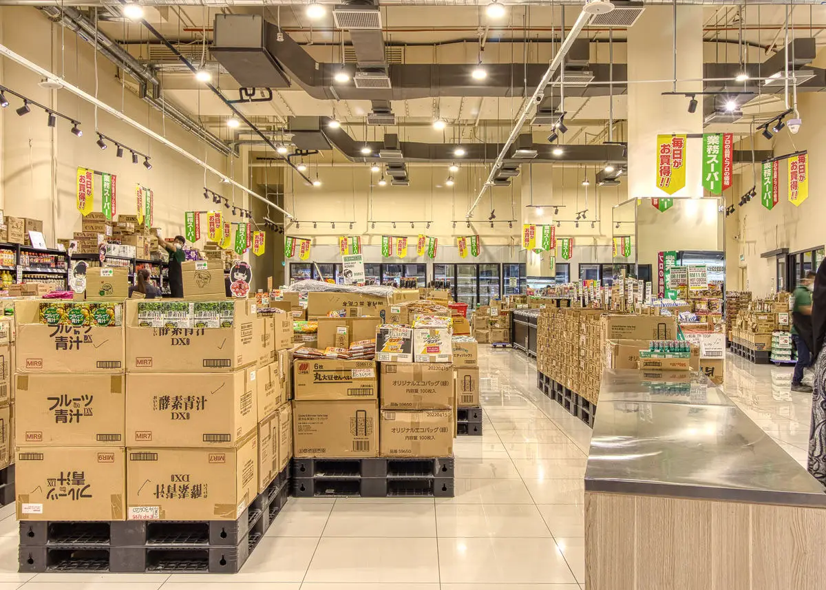 Supermarket floor with pallet displays, hanging promotional banners and chillers