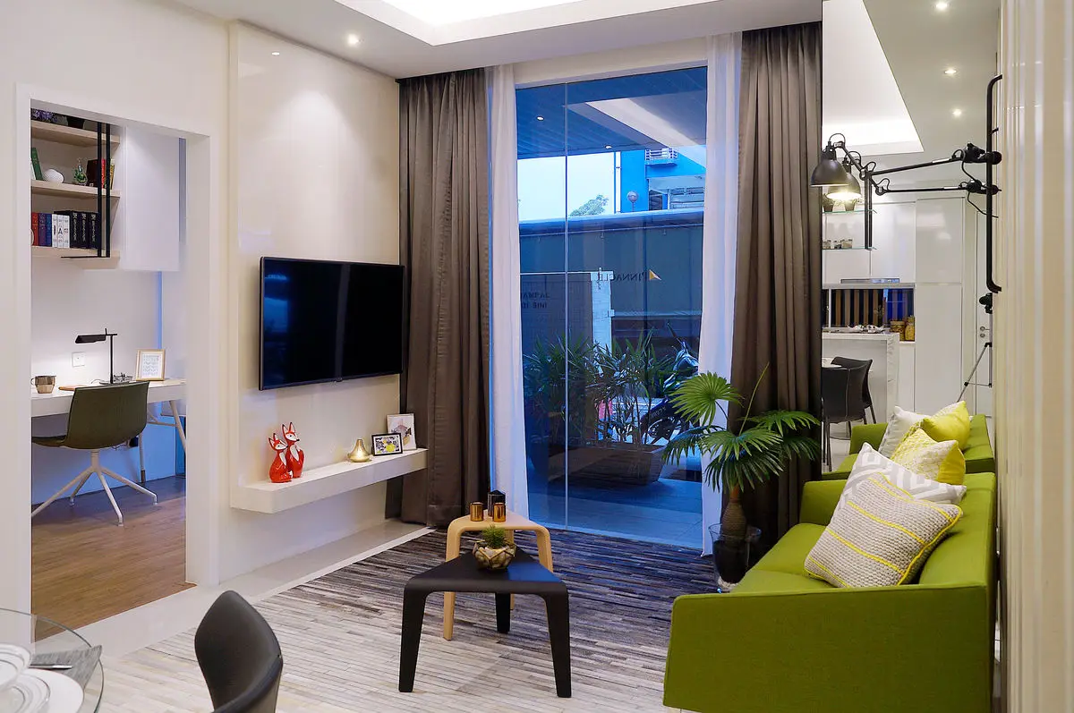 Living room with a wall-mounted TV, green sofa and open shelving beside the balcony