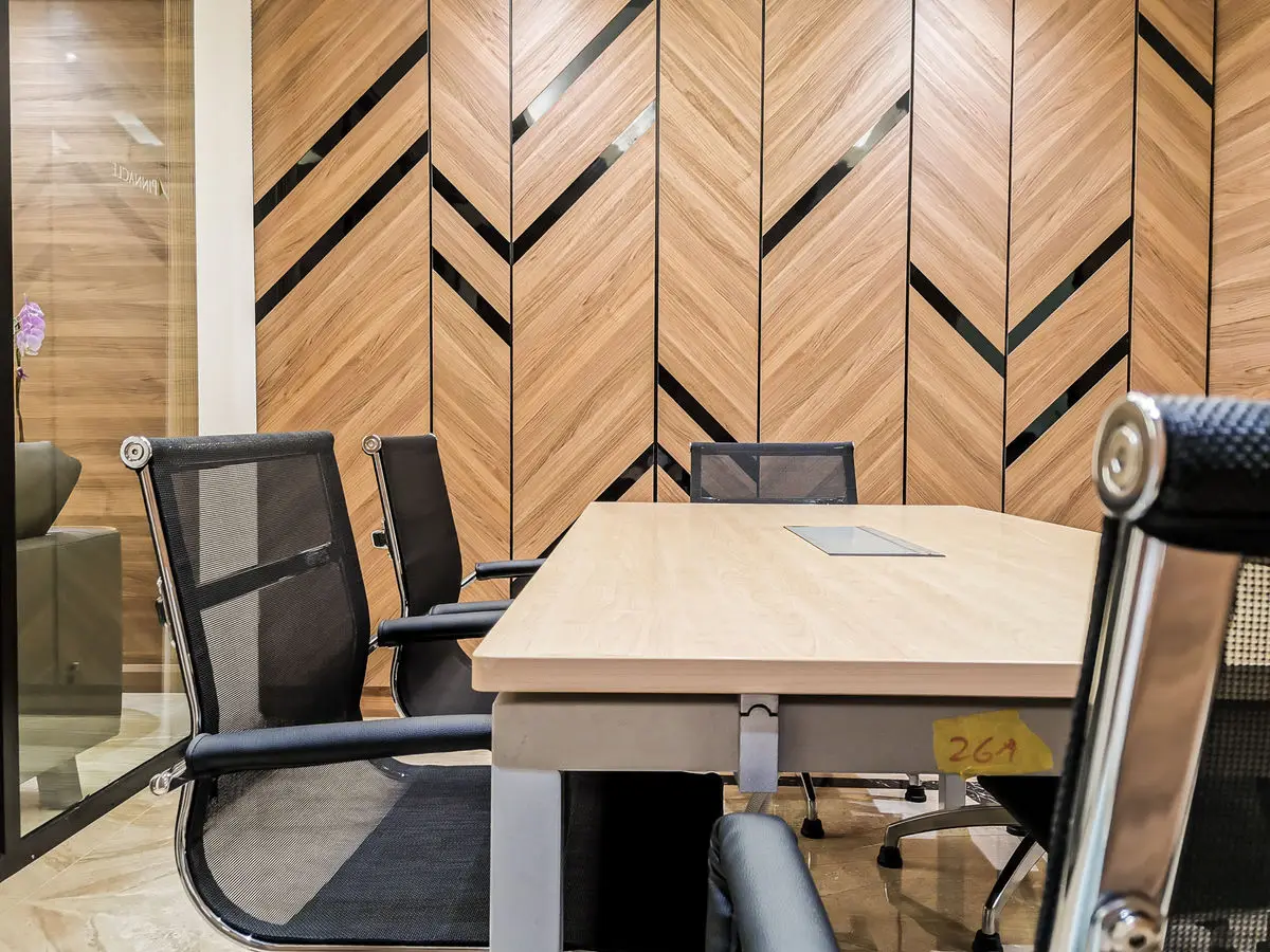 Meeting room detail with mesh task chairs and a patterned timber wall