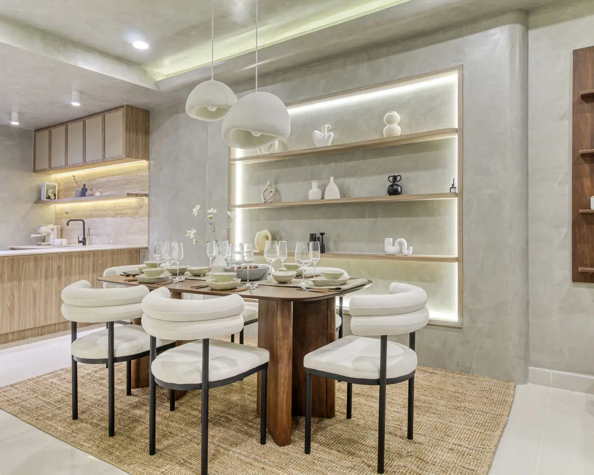 Dining area with a rounded timber table, boucle chairs and backlit display niches