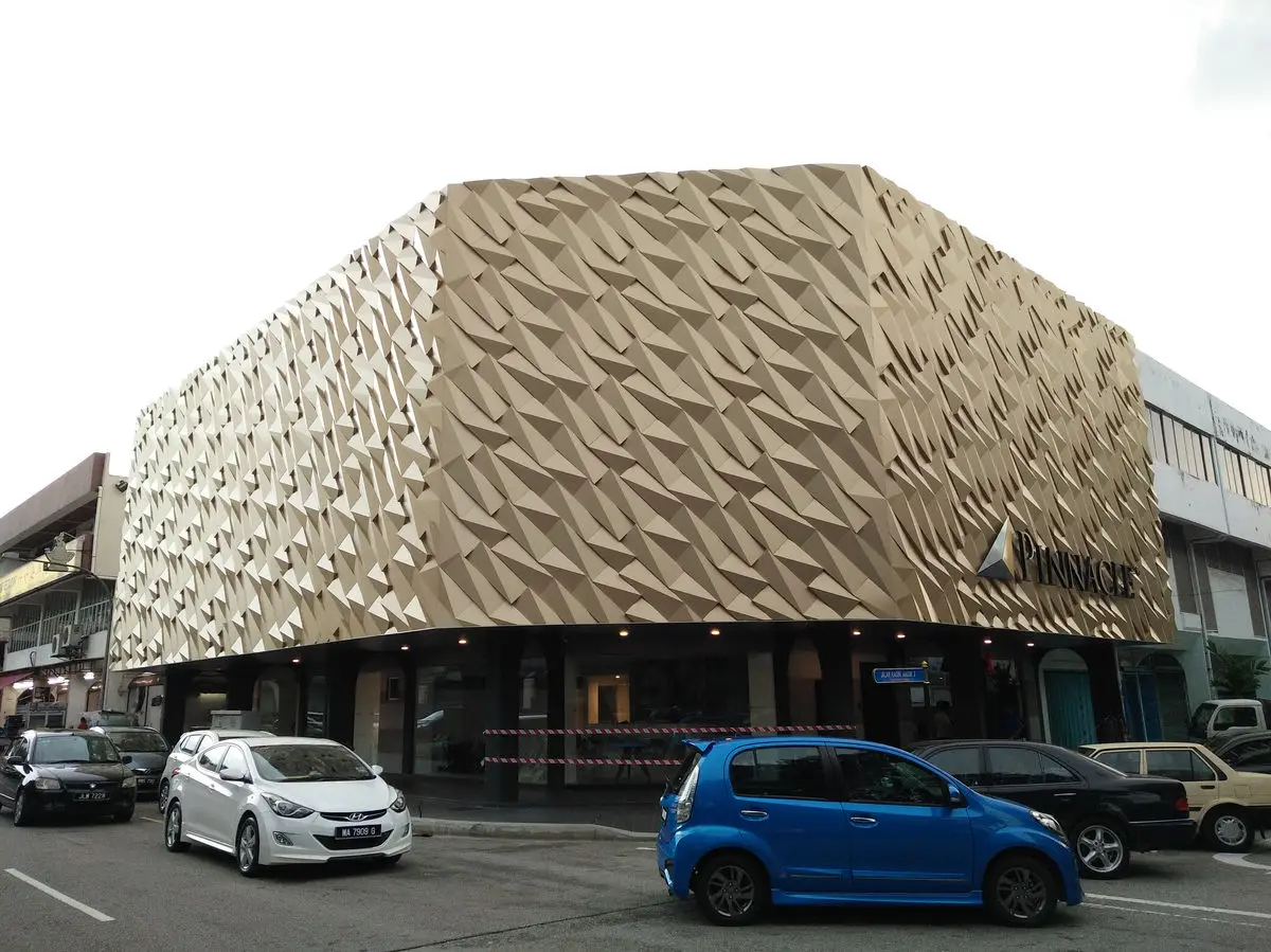 Building exterior clad in a faceted gold panel facade above shopfronts