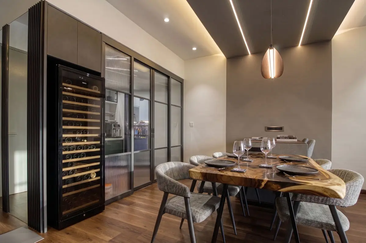 Dining area with a wine fridge, glass partition and a live-edge table