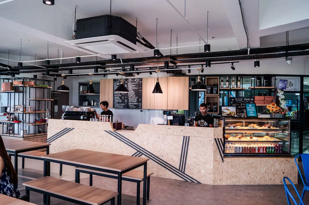 Café with an OSB-clad counter, timber communal tables and blue stools