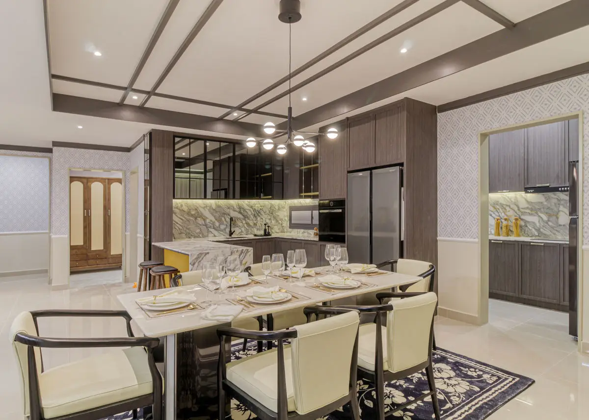 Open kitchen and dining area with a marble island, dark cabinetry and a long dining table