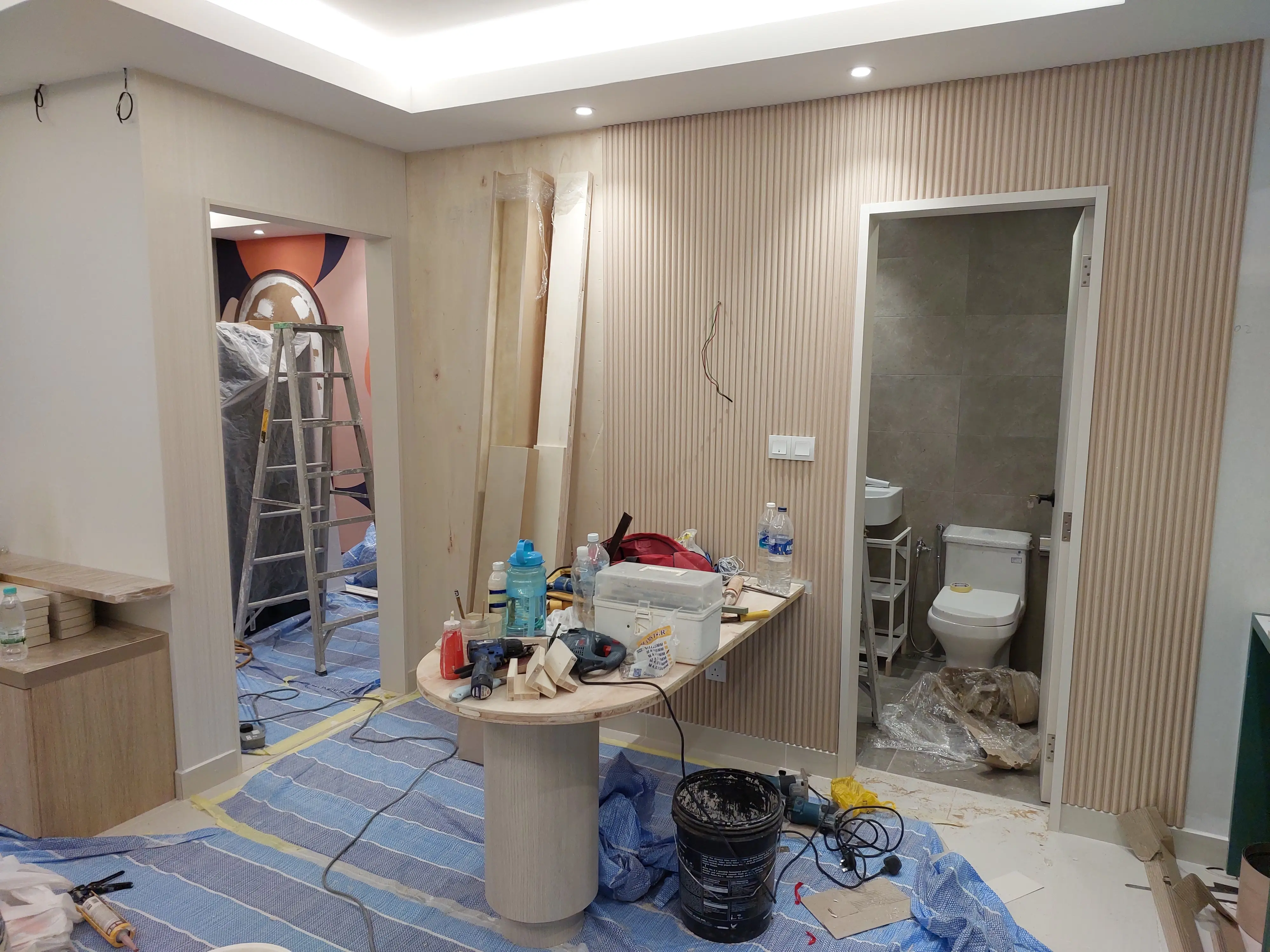 Washroom fit-out underway with fluted timber panelling, tiling and floor protection sheeting