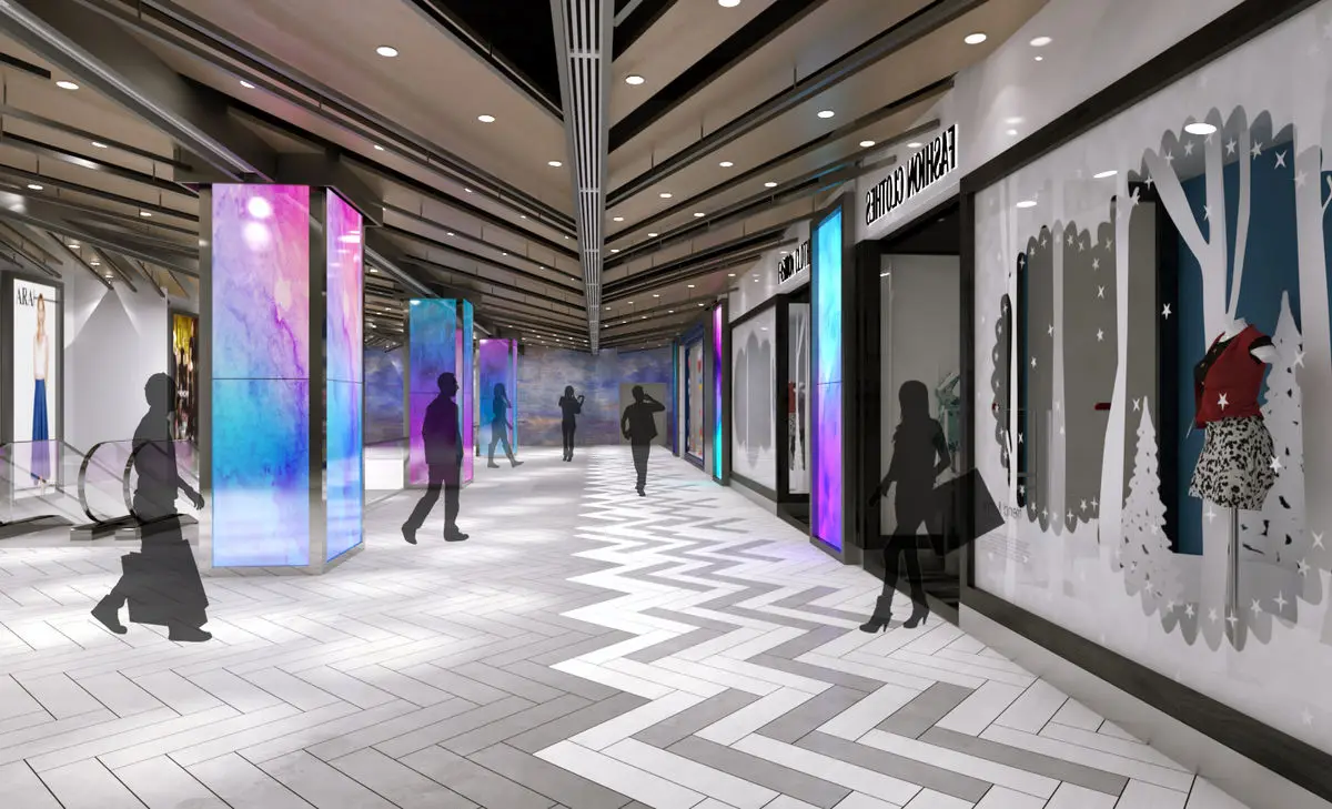 Mall walkway with illuminated media columns and a chevron-patterned floor