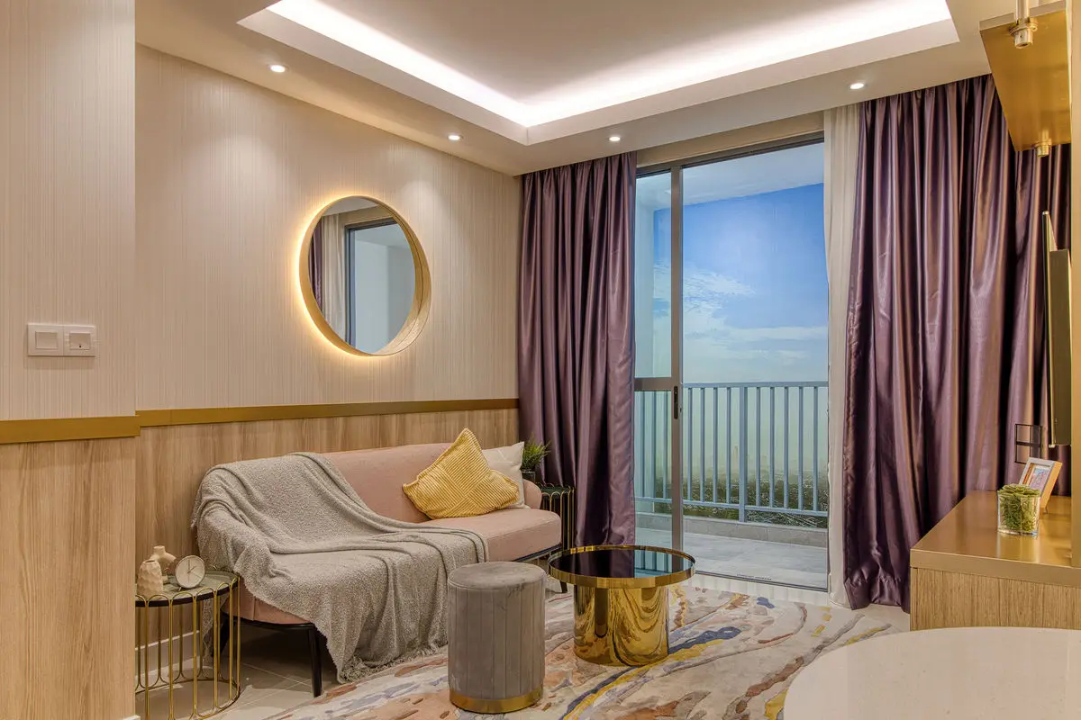 Living room with a round backlit mirror, pale sofa and balcony window