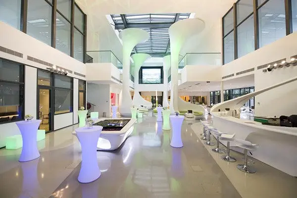 Gallery interior with illuminated cocktail tables and a curved counter