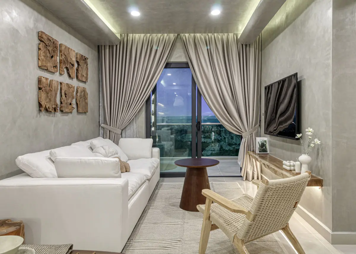 Living room with a white sofa, rattan armchair and cork wall art beside the balcony