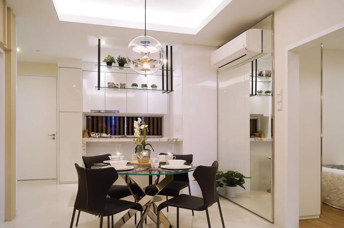 Dining area with a round glass table, black chairs and a mirrored wardrobe wall