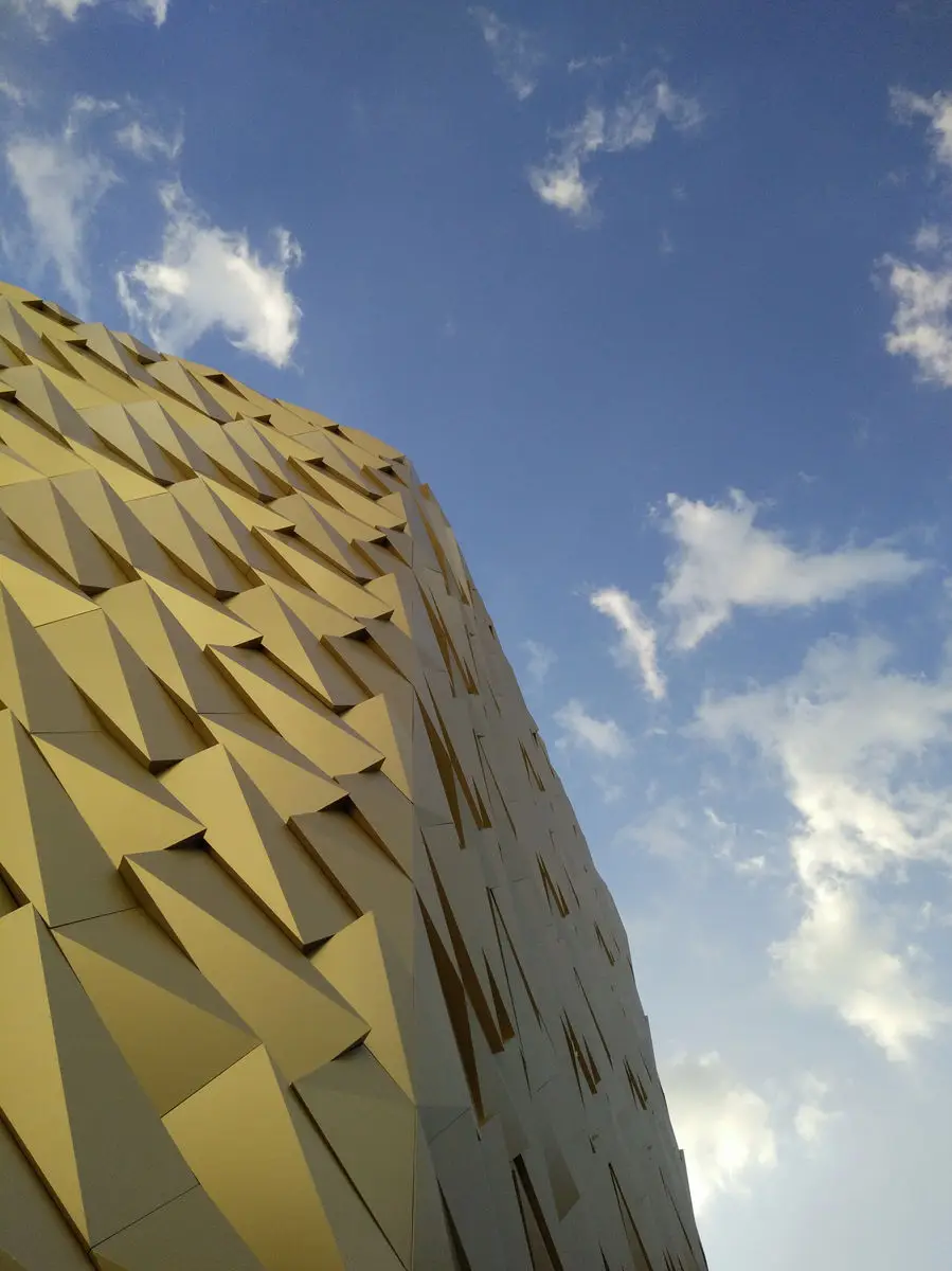 Detail of the faceted gold facade panels against the sky