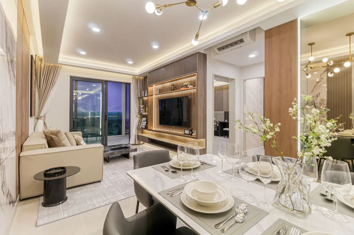 Dining table set for a meal, with the living area and TV wall behind