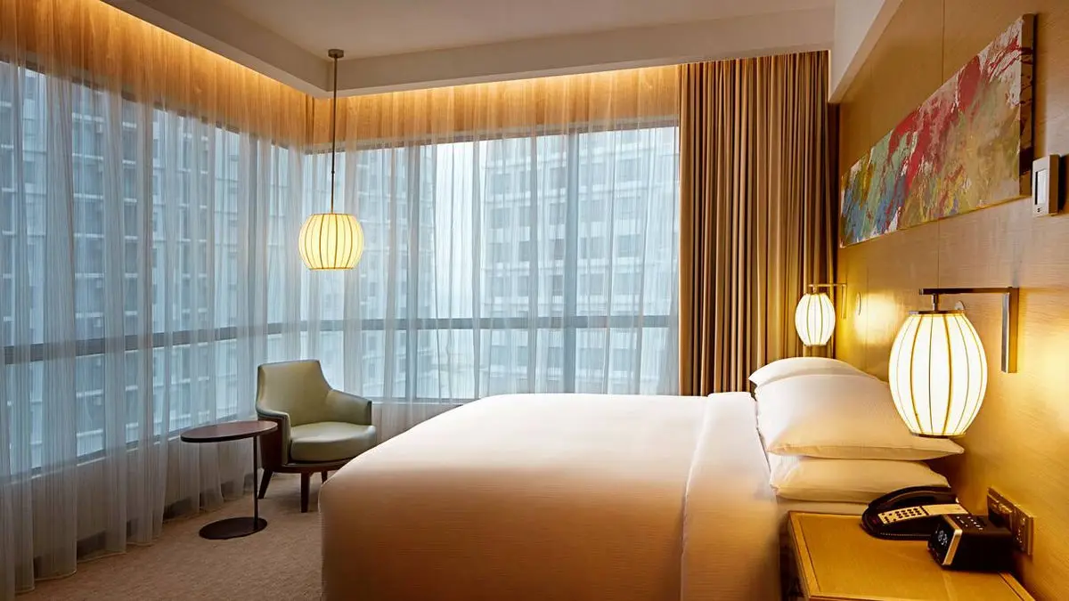 Corner guest room with wraparound glazing, a lounge chair and pendant lighting