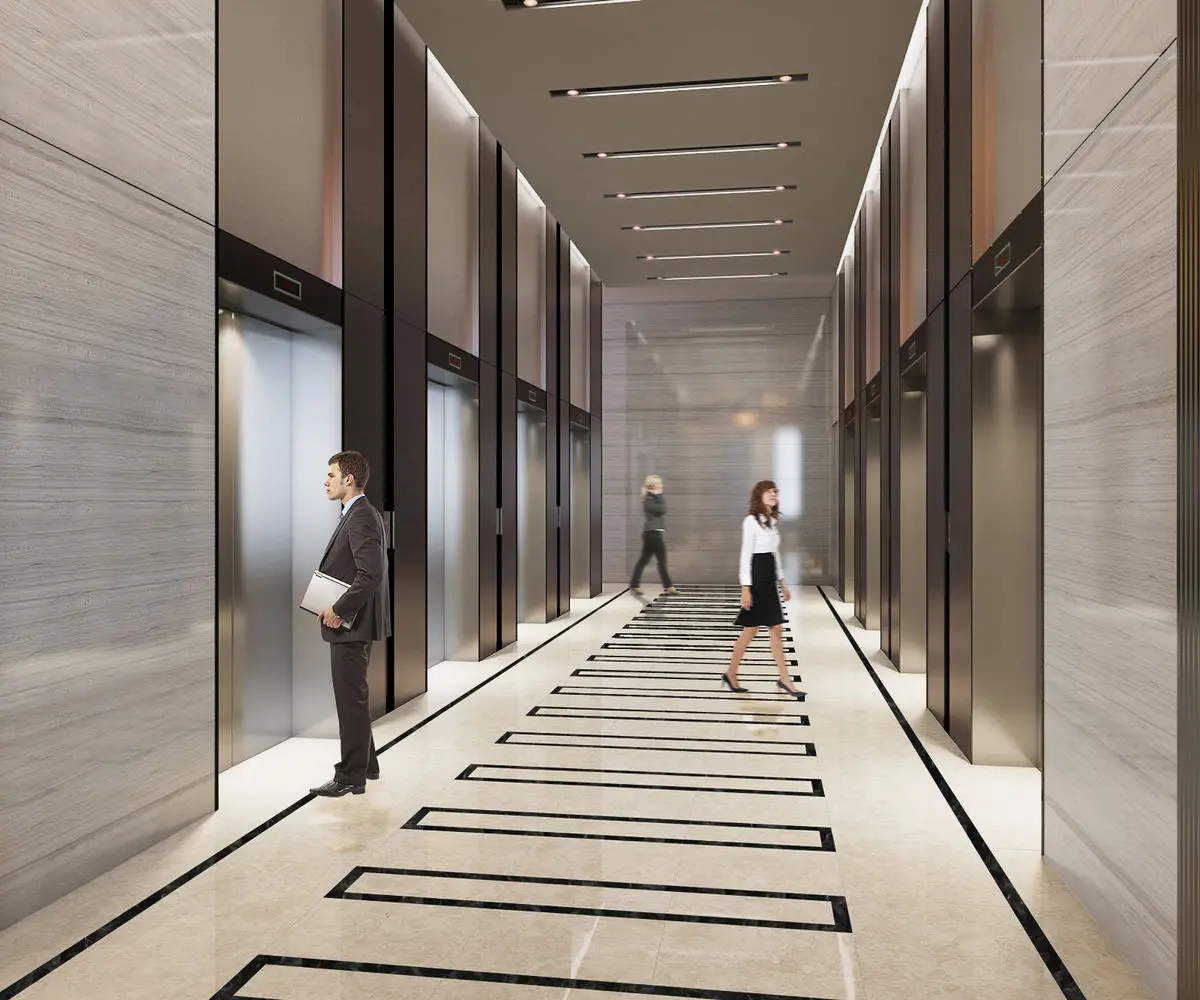 Lift lobby with stone walls, linear ceiling lights and office workers passing