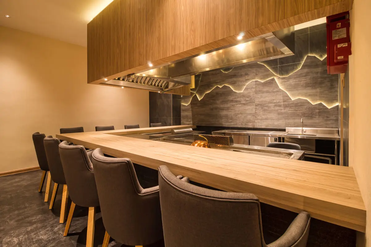 Counter dining with built-in grills, timber worktop and an extraction canopy