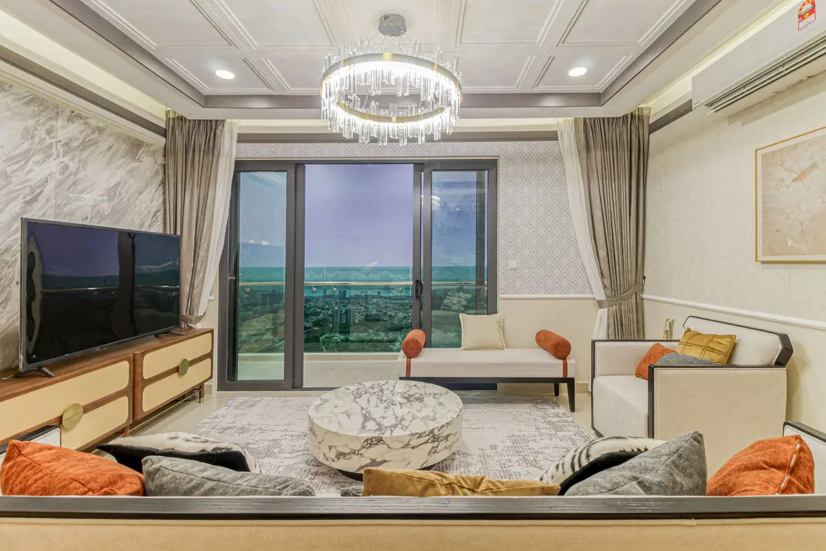 Living room with a marble-topped console under the TV, low seating and a balcony view