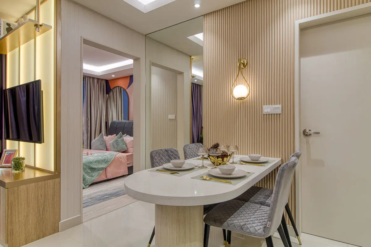 Dining area with a round table, mirrored wall and view through to the bedroom