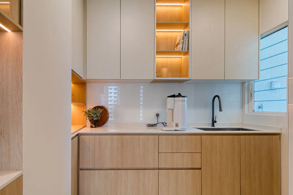Kitchen with a black sink, backlit glass-fronted wall cabinets and a window above the counter