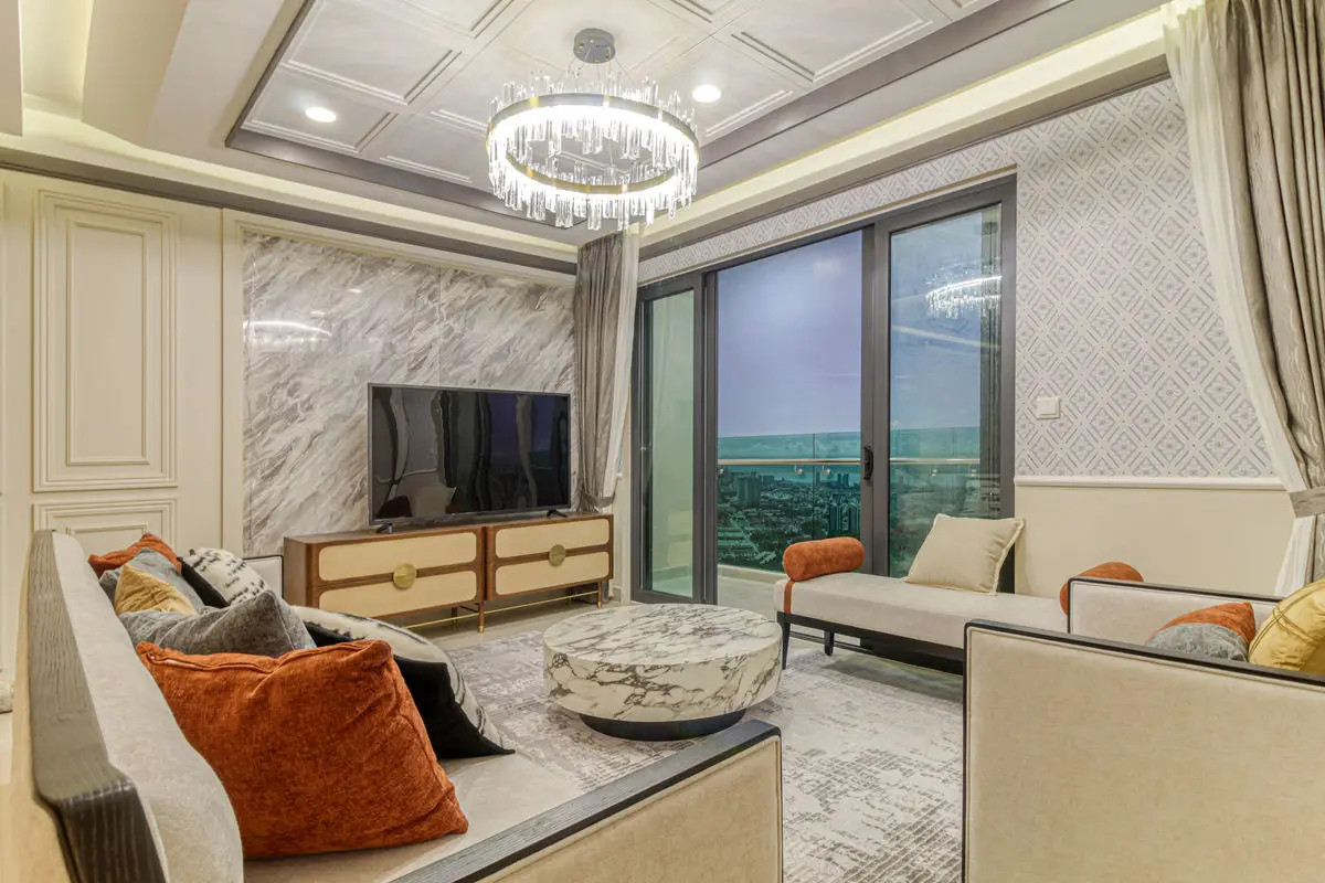 Living room with a chandelier, marble floors and a wide window overlooking the city