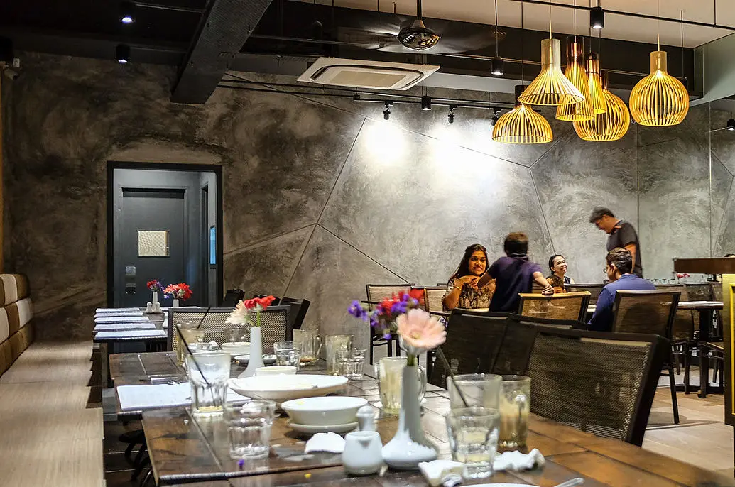 Dining room with concrete walls, rattan pendant lights and set tables