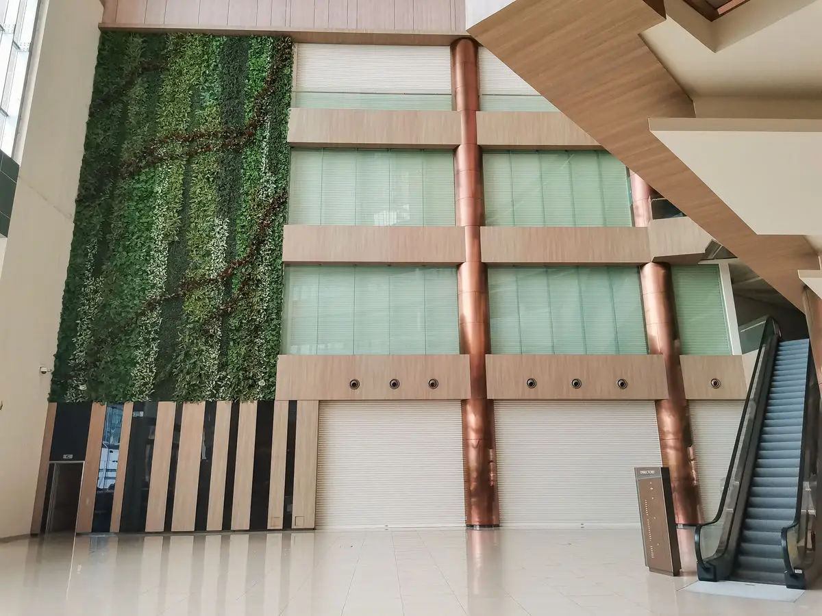Atrium wall with a living green panel, copper columns and escalators