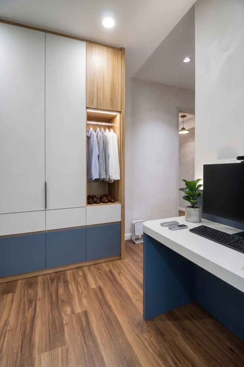 Study with a white desk, navy base cabinets and an open wardrobe beside it