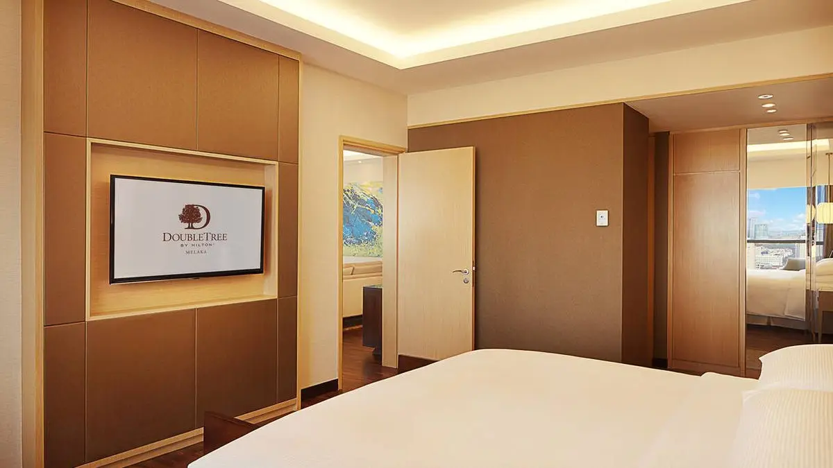 Guest room with a timber-panelled wall, wall-mounted TV and connecting door