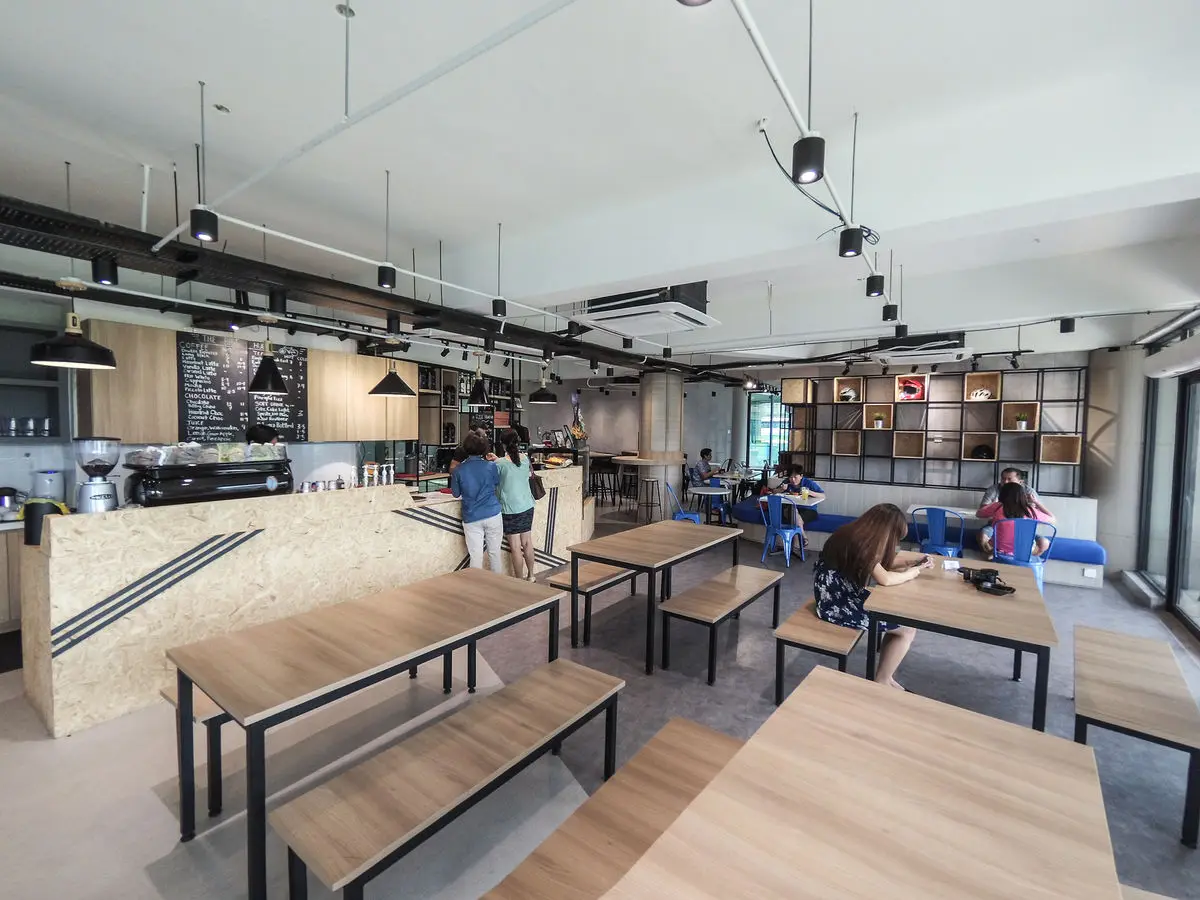 Café seating area with bench tables, track lighting and exposed services