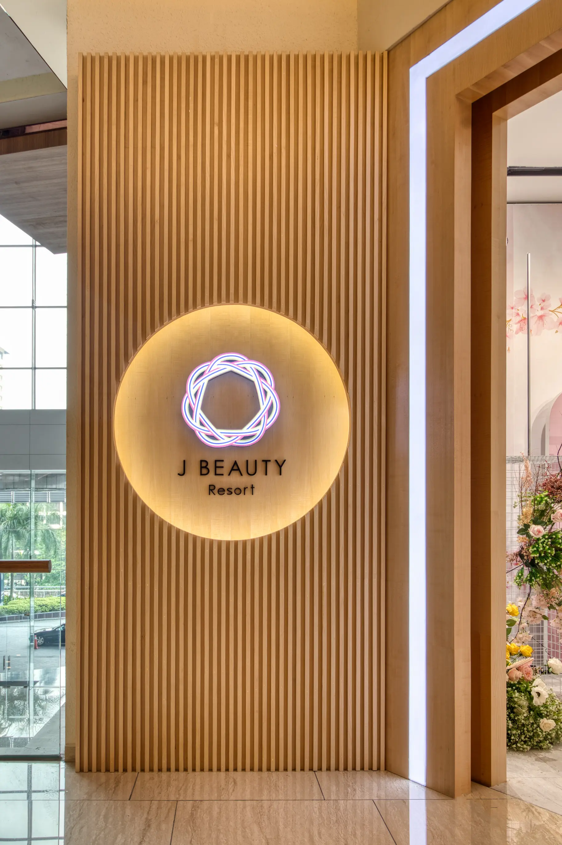 J Beauty Resort entrance with fluted timber screen, backlit circular niche and neon logo
