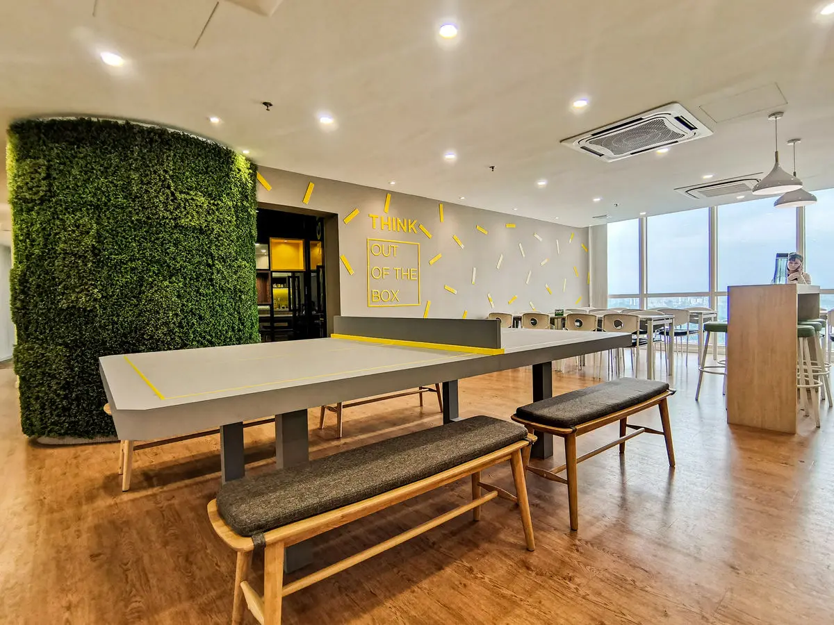 Collaboration area with a long bench table, moss-clad column and window seating