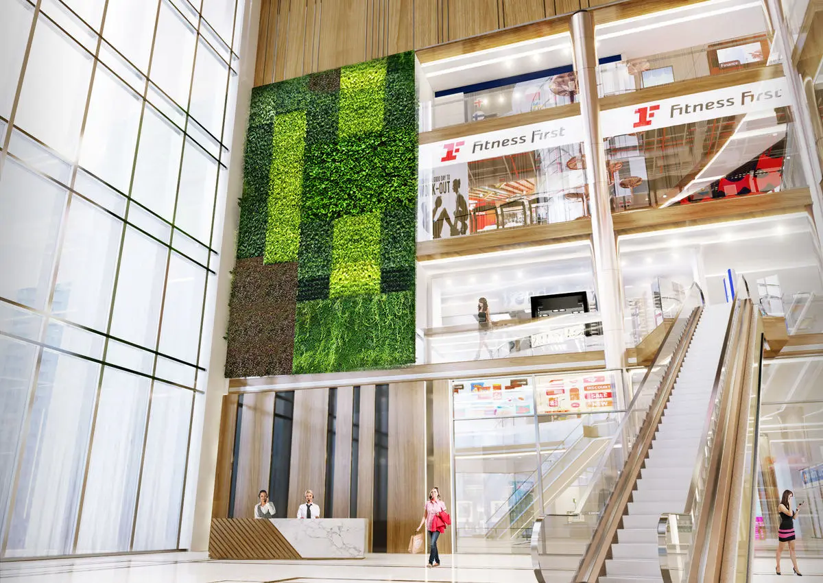 Mall interior with a green wall, escalators and gym signage