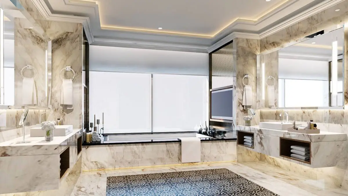 Marble bathroom with a bathtub below the window and twin vanity mirrors