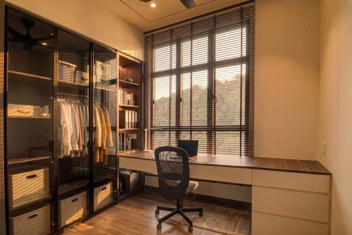 Study and wardrobe with glass-fronted hanging space, a long desk and window blinds