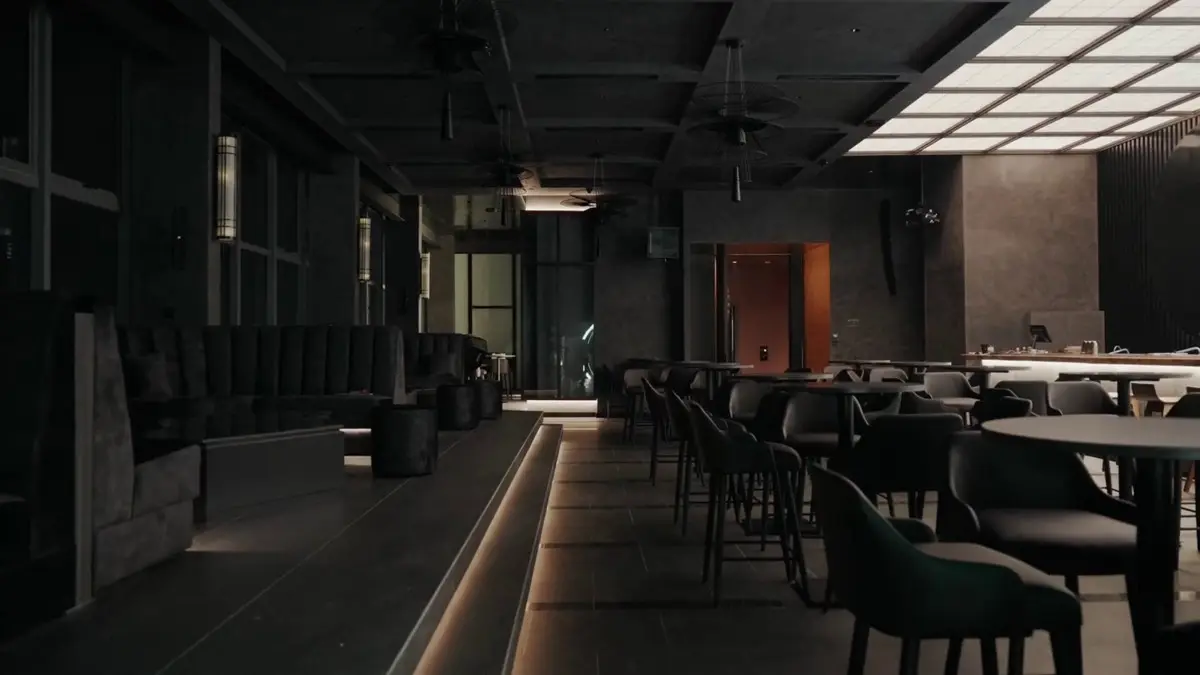 Dining area with dark banquettes, grid ceiling panels and moody lighting